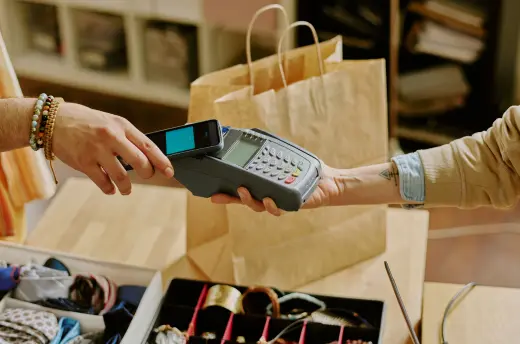A card payment at a retail till beside paper carrier bags