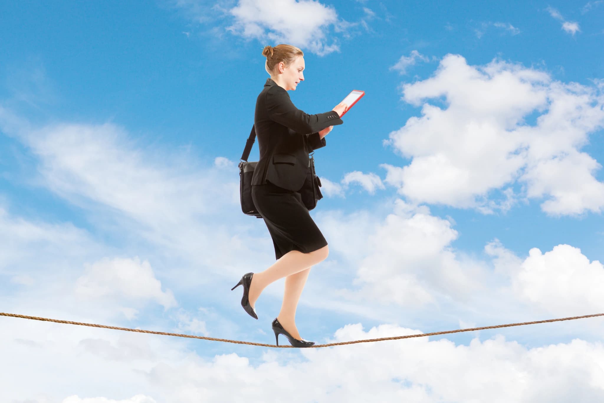 A businesswoman walking a tightrope above the clouds